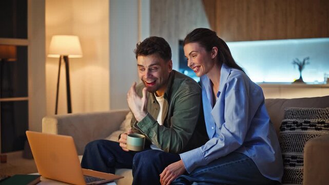 Overjoyed spouses talking virtual conference laptop evening home sitting couch