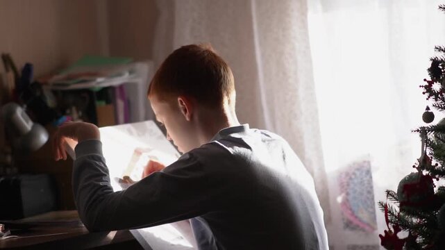 A teenager paints a paint-by-numbers picture on canvas with a brush. A boy dips a brush into paint and creates a creative drawing on a canvas. High quality FullHD footage