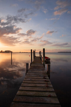 Tranquil seascape with jetty and fishing boat at sunset.
