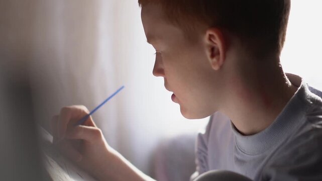 A teenager paints a paint-by-numbers picture on canvas with a brush. A boy dips a brush into paint and creates a creative drawing on a canvas. High quality FullHD footage