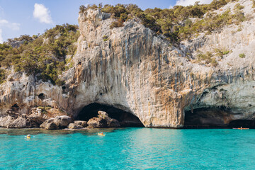 People kayaking in turquoise water near Grotta del Bue Marino cave, Gulf of Orosei, Sardinia, Italy on a sunny day © anatoliycherkas