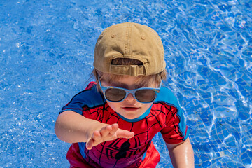 Boy with Down Syndrome Wearing Sunglasses and Cap Playing in Swimming Pool © Валентина Руденька