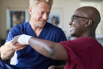 Fototapeta premium Therapist assisting patient with wrist bandage in clinic