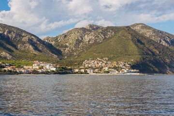 Fototapeta premium Cala Gonone coastal village in Gulf of Orosei, Sardinia, Italy, with residential architecture below green mountains and Mediterranean sea