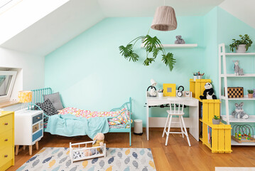Fototapeta premium Interior of child room with bed, yellow furniture and turquoise wall. Wooden floor with design carpet. Colorful apartment in the attic.
