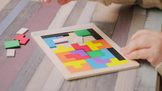 hands carefully placing colorful wooden geometric shapes intellectual puzzle, therapy cognitive training, dementia aid, brain health, occupational therapy, logical thinking, mental exercise