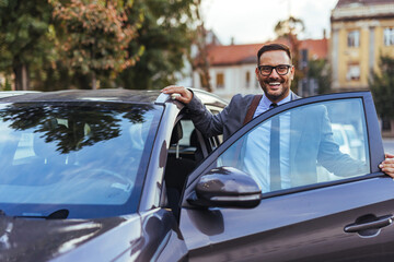 Smiling Businessman Getting Out of Car With Briefcase and Glasses in Urban Morning