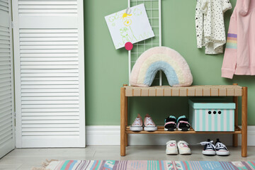 Shoe storage. Shelving unit with different kid's footwear near green wall indoors, space for text © New Africa