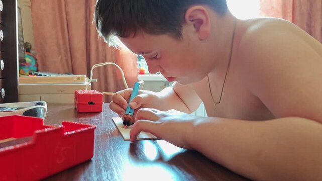 Boy uses burning device to create art on plywood during afternoon craft time