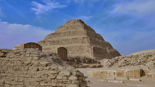 Iconic Step Pyramid of Djoser at Saqqara necropolis near Cairo, Egypt, six-tiered limestone structure towering over surrounding ancient ruined complex.