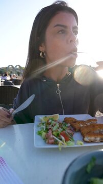 Woman eating fried haddock at seaside restaurant mystical sunset lifestyle