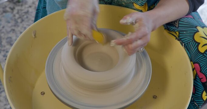 Hands-on pottery: Crafting a delicate ceramic form on a spinning potter's wheel, a close-up perspective captures the artist's skillful hands molding wet clay with precision.