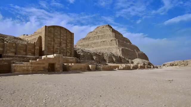 Archaeological site of Saqqara, Egypt, Step Pyramid of Djoser in background with ancient funerary complex ruins, stone blocks and sandy desert foreground.