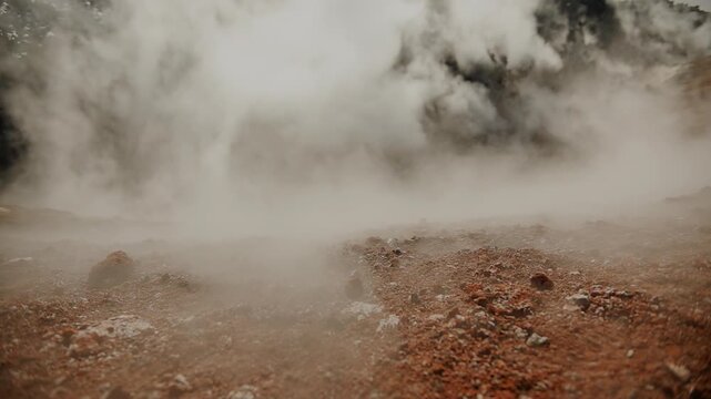 Volcano's crater is filled with dense lava plug and clouds of steam and smoke emerge from cracks and creep along edges in gusts of wind. Concept of volcanic activity