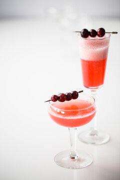 Pink cocktail with fruit garnish on white