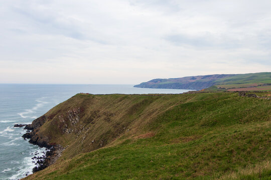 High grassy cliffs and rocky headland at Siccar Point overlooking the North Sea in Berwickshire Scotland