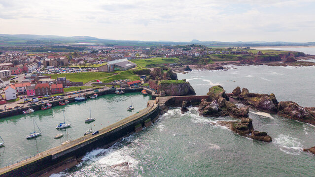 Historic Dunbar Harbour with medieval castle ruins and coastal town landscape along the North Sea in East Lothian Scotland