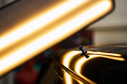 PDR lighting highlights blue glue tab on car roof dent. Plastic tab pulls complex rail dents..