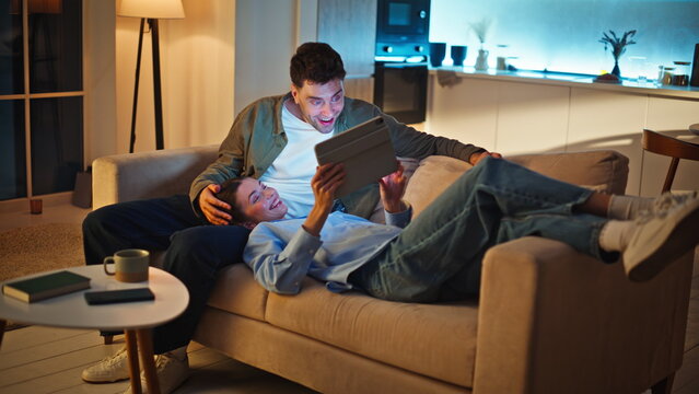 Chilling couple discussing tablet content relaxing together at cozy home sofa