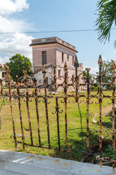 Cuba, Cienfuegos, Punta Gorda.  An old dilapidated villa behind wrought iron fence.