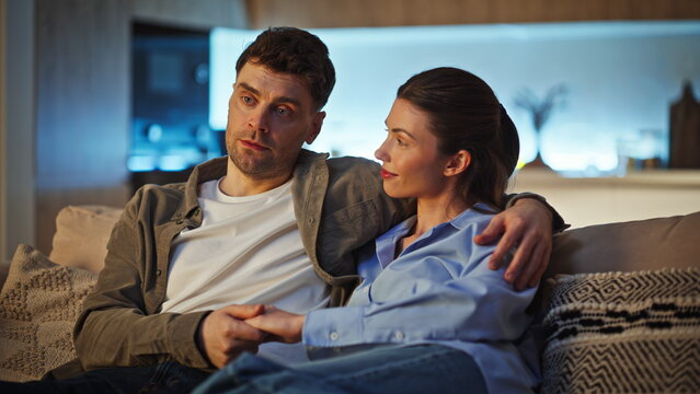 Happy sweethearts relax home in evening lamp light. Closeup man embracing wife