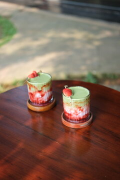 Two refreshing strawberry matcha lattes with fresh strawberries on top, outdoors