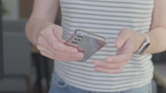 Woman holds smartphone and touches screen, then places device on stand. Concept of mobile browsing and home technology