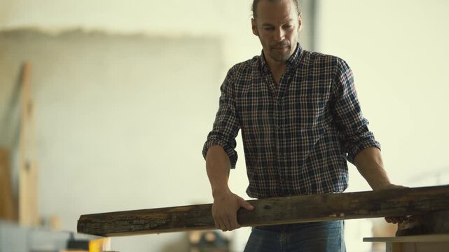 Carpenter preparing wood plank for planing in workshop