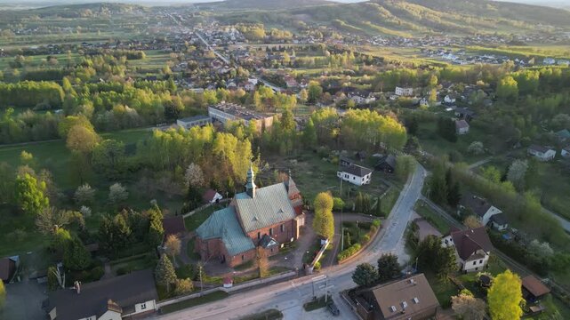 Tumlin - wojew&oacute;dztwo Świętokrzyskie - Polska - piękny zach&oacute;d słońca nagrany dronem. Kości&oacute;ł, g&oacute;ra Grodowa, zielone wzg&oacute;rza, ujęcia kinowe