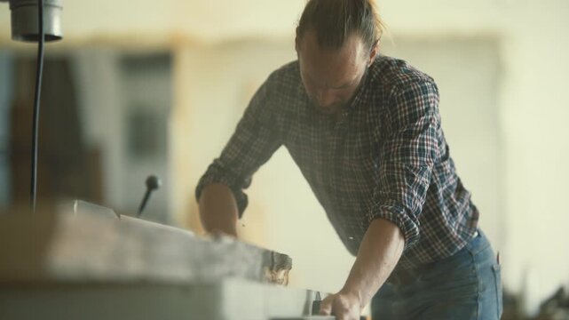 Professional carpenter planing a wooden plank in his workshop