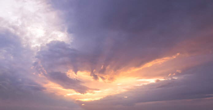 Dramatic sunset sky with golden sun rays piercing through dark clouds for natural backdrop and spiritual hope concept design