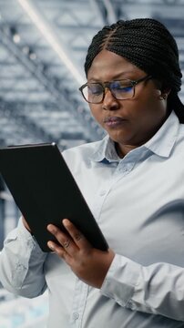 Vertical video Reviewing schematics, semiconductors and portrait of smiling woman in smart factory. Overseeing layouts, EDA software and cheerful african american businesswoman in industry 4.0 plant