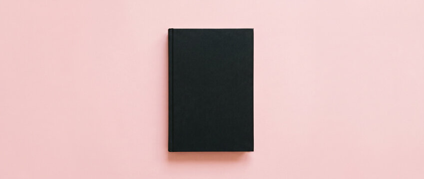  Minimalist flat lay mockup of a black hardcover notebook or diary on a light pink background for branding presentation.
