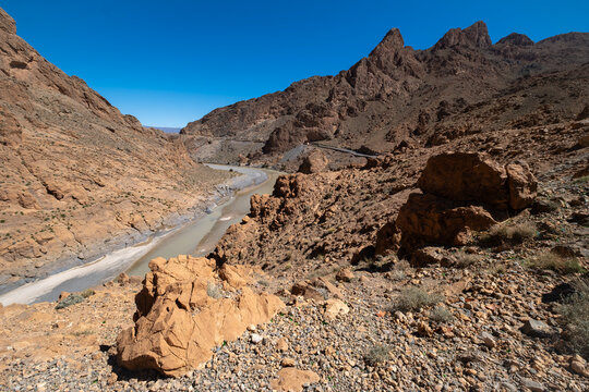 view of the Ziz River winding through a deep rocky gorge with dramatic cliffs in the High Atlas Mountains of Morocco under a clear blue sky