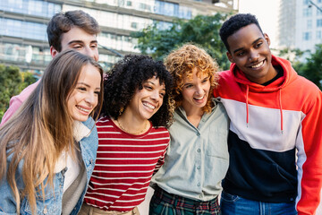 Fototapeta premium Multicultural group of friends having fun outdoors. Happy young people are enjoying friendship and laughter in a green urban area. Social connection and lifestyle concept.