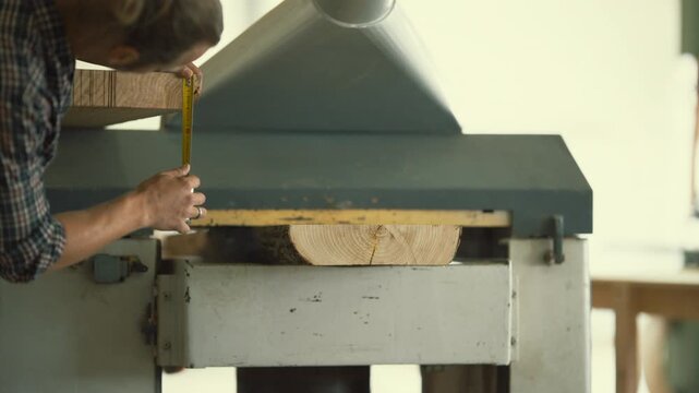 Carpenter using a thickness planer woodworking machine