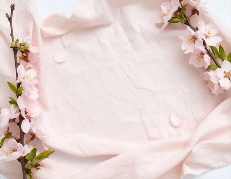 Cherry blossom branches and petals on pink linen fabric, flat lay spring floral background