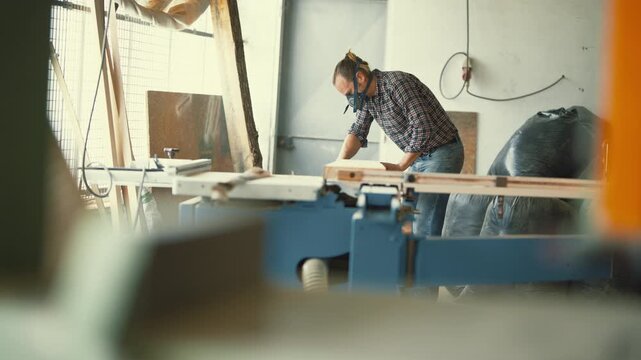 Carpenter with respirator mask working on a woodworking machine