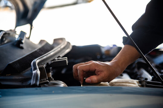 Close up Car Mechanic man hands repairing car auto repair shop. Close up hand man check engine oil level Locate dipstick, wipe clean, check dipstick level before fill up engine oil. open vehicle