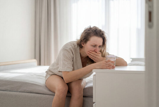 Pregnant woman feeling sick with morning sickness in her bedroom