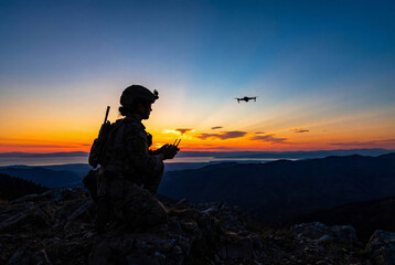 Naklejka premium Silhouette of female soldier operating drone on mountain peak at sunset