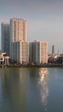 Modern skyscrapers reflect in a calm lHo Sinh Thai, Quy Nhon, Binh Dinh, Vietnam. The city skyline features residential and commercial buildings.