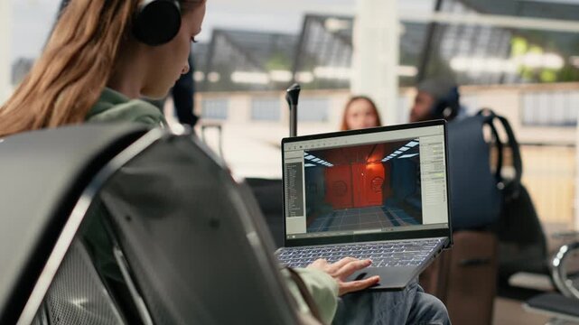 Digital nomad game developer working on laptop in international airport lounge, developing video game with futuristic spaceship while waiting for flight departure. Freedom to work anywhere.