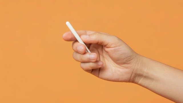Holding the Chalk: A hand delicately holds a piece of chalk, set against an orange backdrop, evoking the feeling of an artist at work or a teacher preparing for class. 