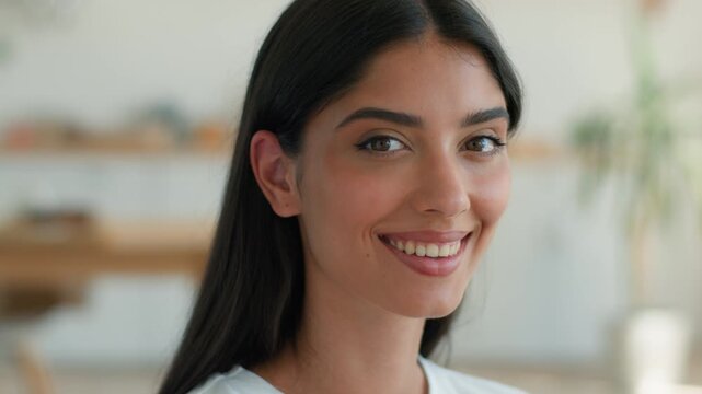 Confident smiling Indian Arabian woman looking at camera home indoors young female portrait happy professional model lady with toothy white smile pretty face close up business girl inside living room