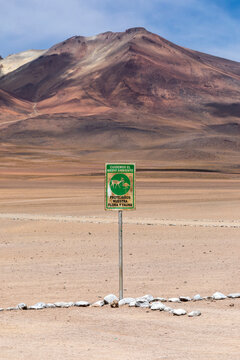 Spanish Conservation Sign Protecting Flora and Fauna with Colorful Andean Volcano, Siloli Desert, Bolivia