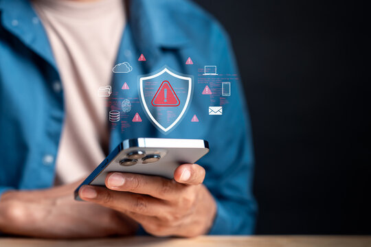 Person using smartphone with cyber security shield and warning sign. Data protection, antivirus and scam alert concept.