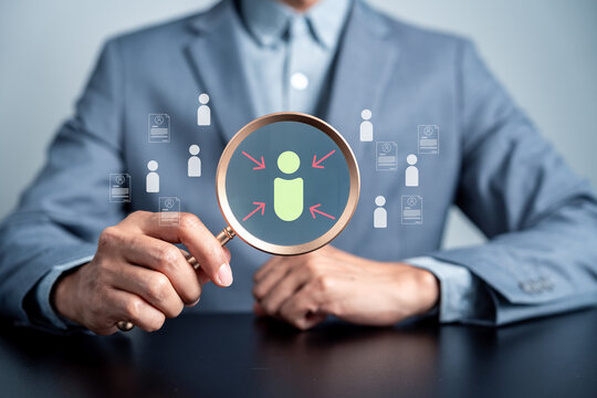 usinessman holding magnifying glass over candidate icon. Human resources, recruitment and talent acquisition concept.
