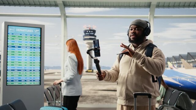 Solo male traveler, recording video blog, in airport terminal lounge, sharing travel tips and holiday experiences with online audience. Influencer culture, and the freedom of content creation.