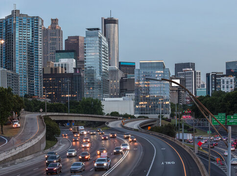 View of the Downtown Atlanta Skyline Cityscape showing several prominent buildings, highways, cars, and hotels on a beautiful clear evening after sunset as seen from a city street.
